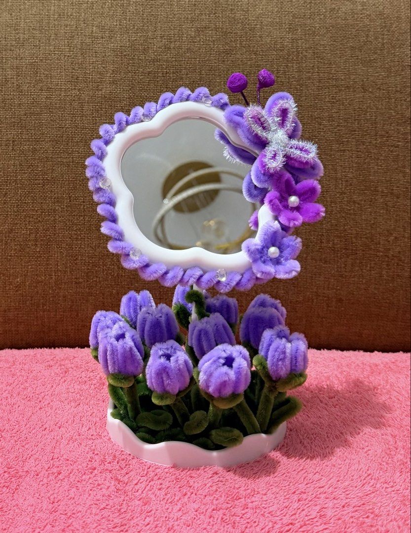 Handmade Pipe Cleaner Flower Desk Mirror (Category: Mirrors) located in Dasmarinas. Submitted by ligean2738954 (Listing ID 1464724886, Image 1). Description: Custom handmade vanity mirror decorated with fluffy pipe cleaner flowers and butterfly accents. Available in two colorways: purple or pink and red. Stands securely in a white scalloped base. Cute decor piece for a vanity table, desk, or bedside table. Bright and cheerful room accessory..
