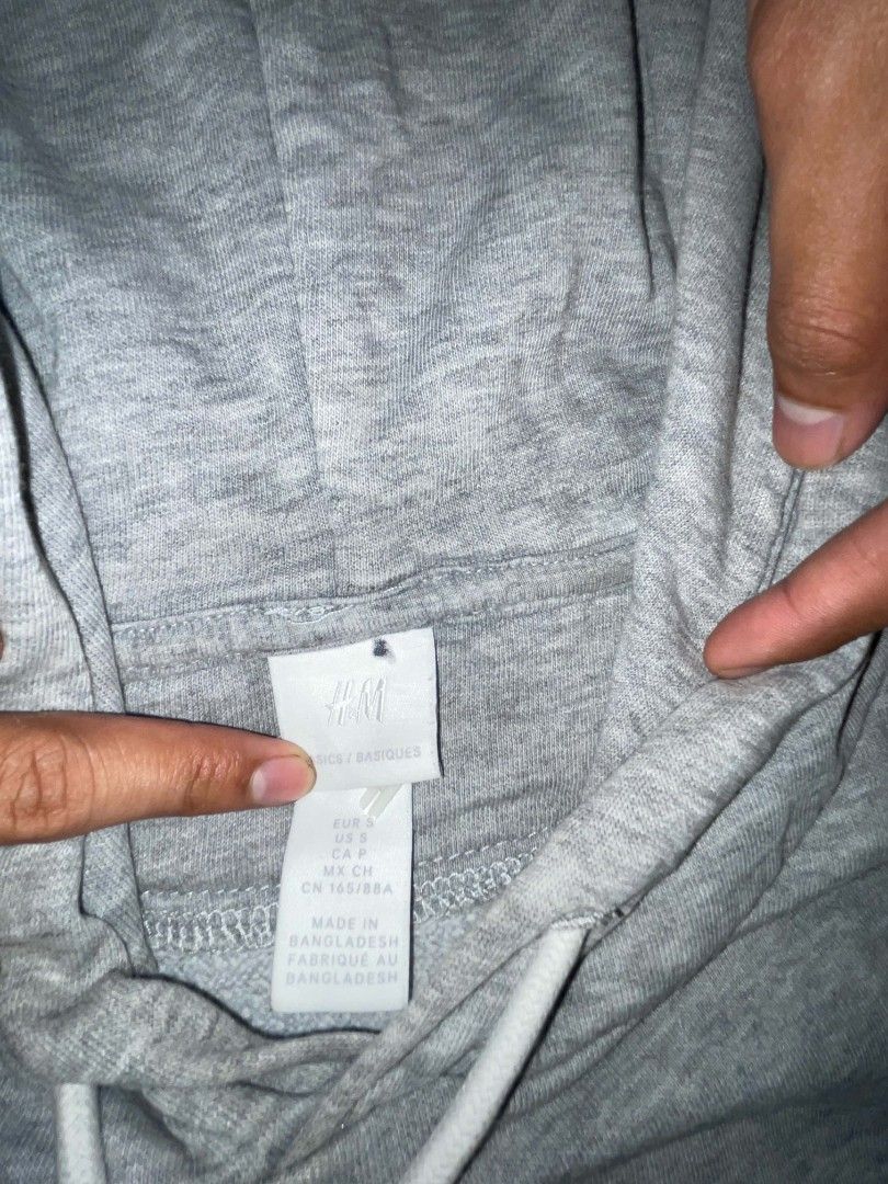 H&M Grey Hoodie Boxy Type (Category: Coats, Jackets and Outerwear) located in Manila. Submitted by joshthrifts (Listing ID 1464702824, Image 2). Description: - Brand: H&M - Size: Small (Regular fit) - Color: Grey - Material: Cotton, polyester, and viscose blend - Features: Front kangaroo pocket, adjustable white drawstrings - Condition: Pre-loved with visible wear and staining on the fabric and cuffs - Style: Classic casual wear.