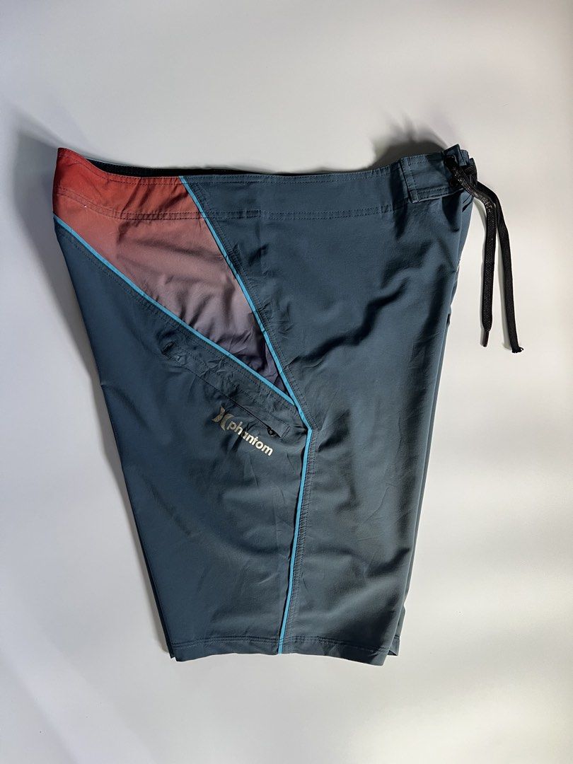 Hurley Phantom Board Shorts Swim Trunks (Category: Swim Trunks & Board Shorts) located in Baler. Submitted by allthrifted31 (Listing ID 1464732102, Image 3). Description: - Brand: Hurley Phantom - Color: Dark grey with blue and reddish-orange gradient panels - Fabric: Performance stretch, lightweight, and quick-drying - Features: Secure zippered side pocket with logo, adjustable drawstring waist - Condition: Excellent for surfing, swimming, and b