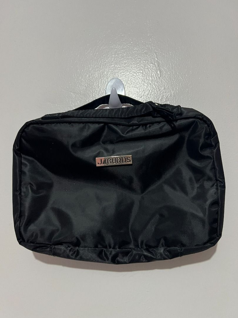 Jagurds Hanging Travel Bag (Category: Sling Bags) located in Davao. Submitted by jpnusapasabuyfindsdvo (Listing ID 1464698693, Image 2). Description: - Brand: Jagurds - Color: Classic Black - Multiple zippered compartments with clear plastic windows for easy visibility - Built-in sturdy hook for convenient hanging on doors or bathroom fixtures - Compact foldable design transforms into a neat rectangular pouch - Stylish silver logo plate detail on