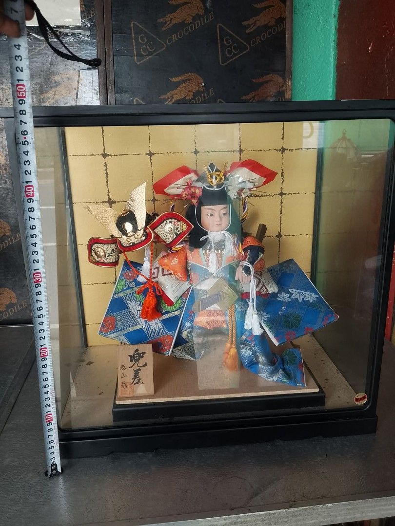 Japanese Samurai Doll in Display Case (Category: Vintage Collectibles) located in Quezon City. Submitted by jpnvintageonline (Listing ID 1464597189, Image 3). Description: - Beautiful Japanese doll dressed as a samurai. - Comes in a protective display case with a gold patterned background. - Doll wears a colorful kimono and traditional headwear. - Includes a small wooden plaque with Japanese writing at the base. - Display case measures approximat