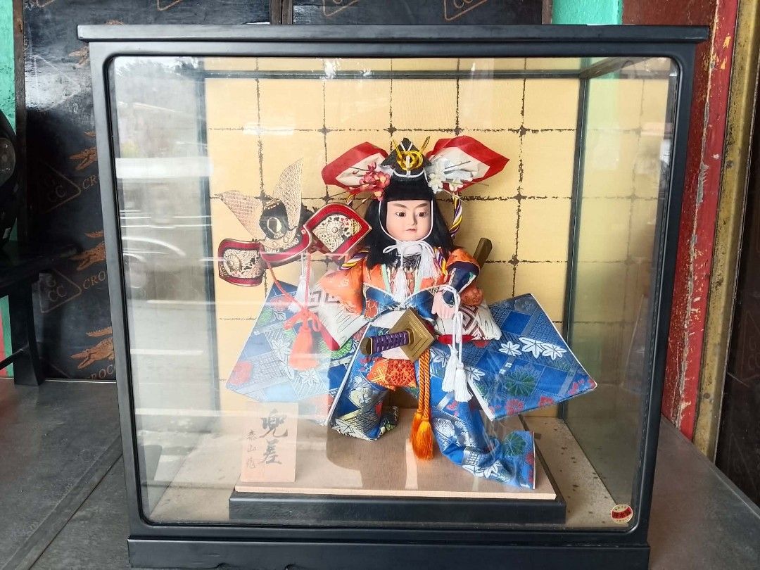 Japanese Samurai Doll in Display Case (Category: Vintage Collectibles) located in Quezon City. Submitted by jpnvintageonline (Listing ID 1464597189, Image 2). Description: - Beautiful Japanese doll dressed as a samurai. - Comes in a protective display case with a gold patterned background. - Doll wears a colorful kimono and traditional headwear. - Includes a small wooden plaque with Japanese writing at the base. - Display case measures approximat