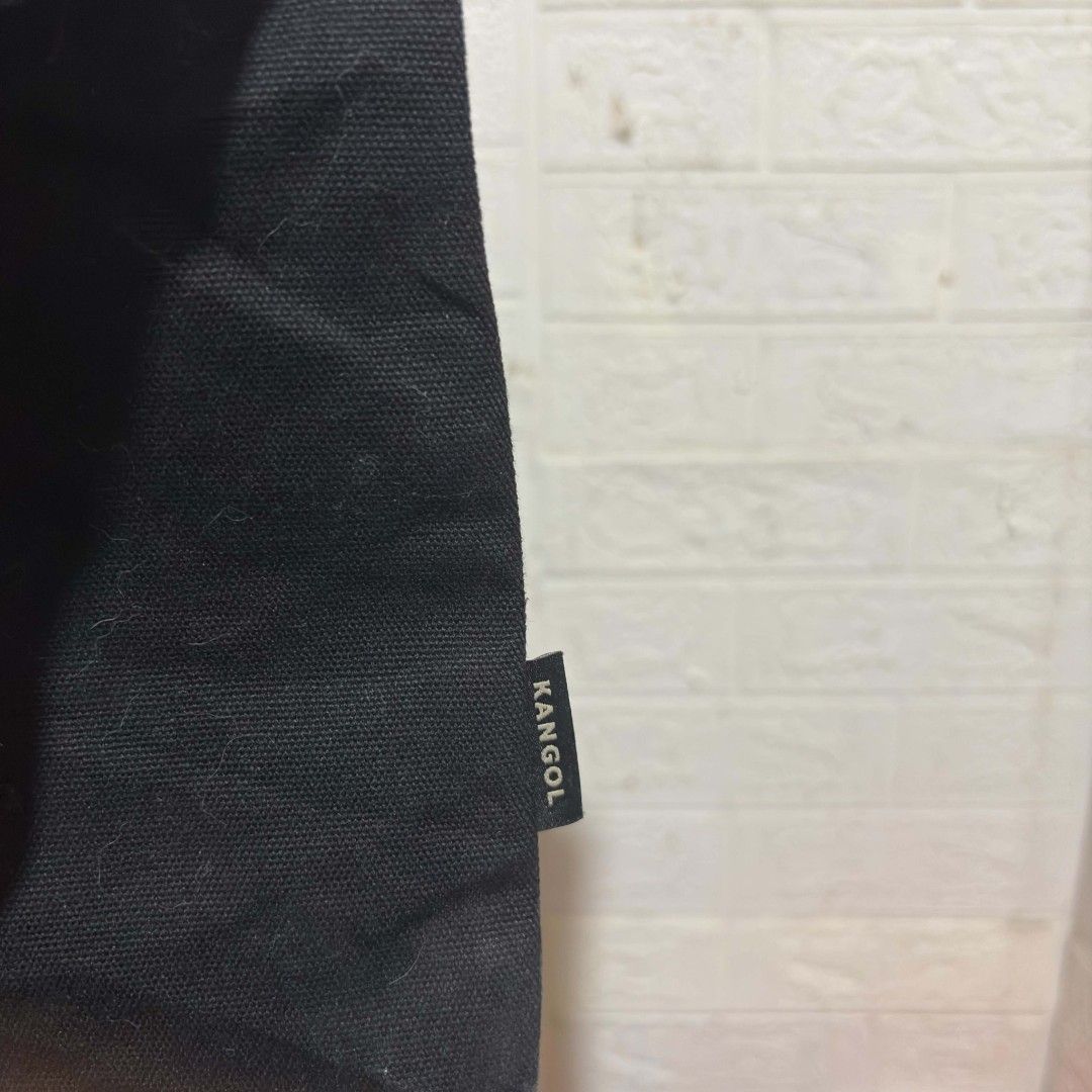 Kangol Black Canvas Tote Bag (Category: Tote Bags) located in Carmen. Submitted by ar_thrift00 (Listing ID 1464715206, Image 3). Description: - Brand: Kangol - Color: Classic Black with large white kangaroo logo - Material: 100% Cotton Canvas - Closure: Secure snap button - Storage: Roomy main compartment with inner pocket - Versatility: Includes top carry handles and an adjustable shoulder strap - Model: KOEB-EB00370 - Condition: Excellent every