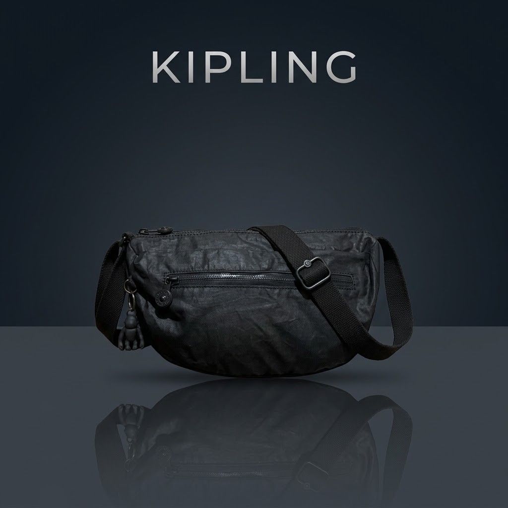 Kipling Black Crossbody Bag with Monkey Keychain (Category: Cross-body Bags) located in Carmen. Submitted by ar_thrift00 (Listing ID 1464712083, Image 1). Description: - 100% Authentic Kipling black crossbody bag made from durable crinkled nylon - Includes the iconic black monkey keychain - Front zipped pocket for quick-access essentials - Spacious main compartment with stylish black-and-white checkered lining and internal zip pocket - Adjustable
