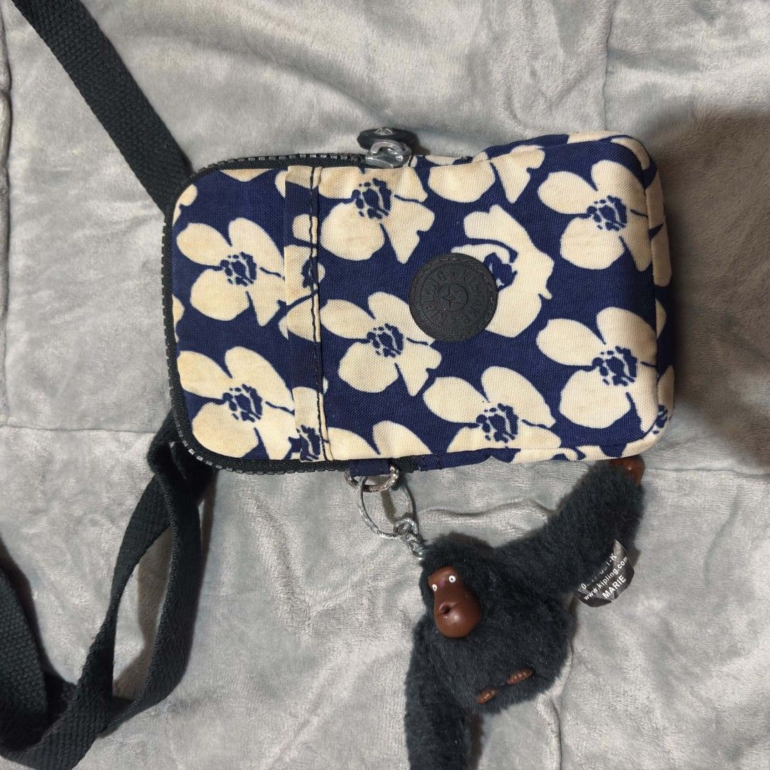 Kipling floral print crossbody bag with monkey keychain (Category: Cross-body Bags) located in Carmen. Submitted by ar_thrift00 (Listing ID 1464713930, Image 3). Description: - Style: Casual everyday crossbody bag - Material: Lightweight navy blue and white floral canvas - Strap & Hardware: Adjustable black strap and sturdy zippers - Pockets: Convenient front slip pocket and secure main zip compartment - Bonus: Includes a cute black furry Kipling