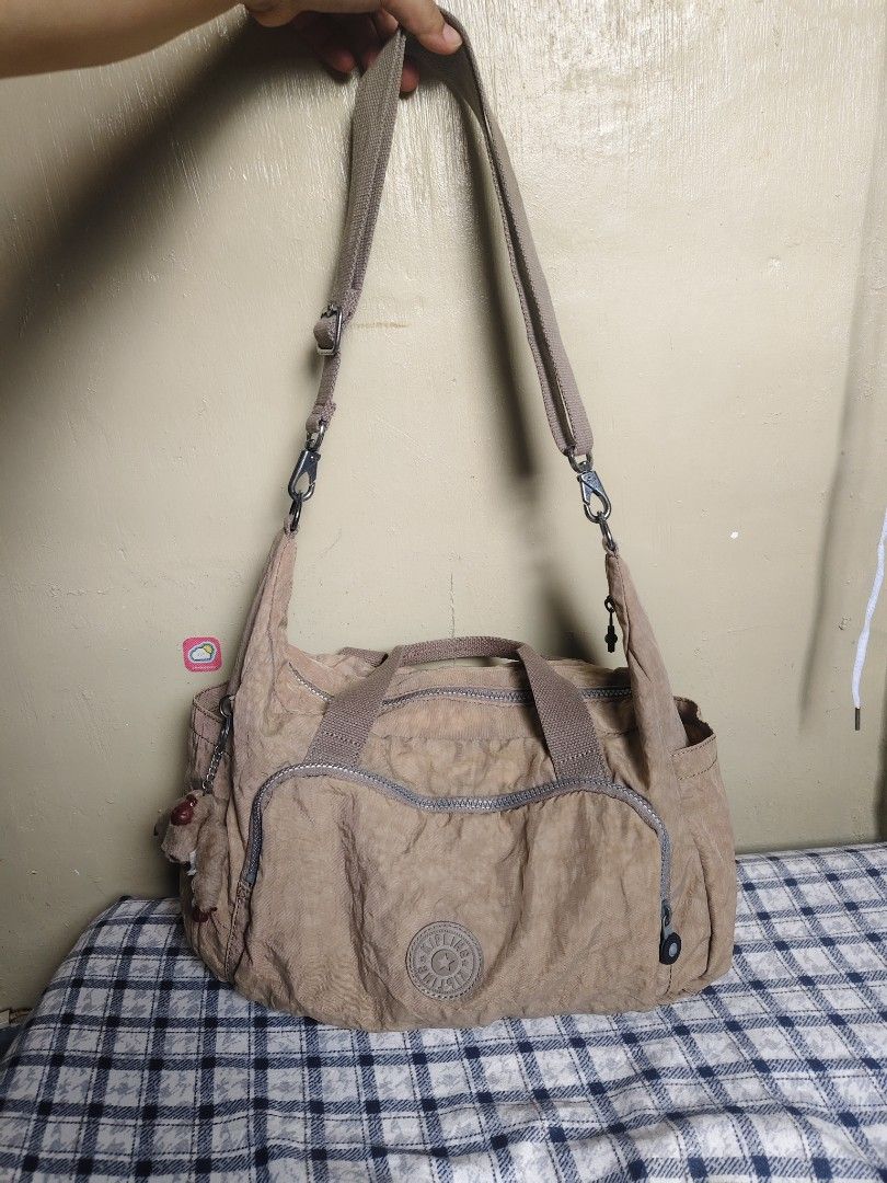 Kipling Shoulder Bag Tan Nylon (Category: Shoulder Bags) located in General Mariano Alvarez. Submitted by findsandmoreph (Listing ID 1464572295, Image 1). Description: - Tan Kipling shoulder bag - Made of durable crinkled nylon - Two comfortable top handles - Detachable shoulder strap for versatile carrying - Multiple zippered pockets on the front for organized storage - Iconic Kipling monkey charm included - Ideal everyday bag for your essential