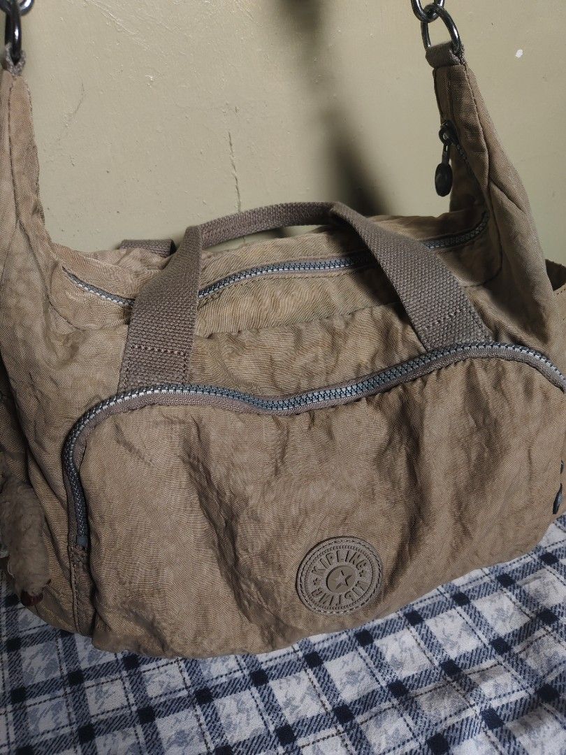 Kipling Shoulder Bag Tan Nylon (Category: Shoulder Bags) located in General Mariano Alvarez. Submitted by findsandmoreph (Listing ID 1464572295, Image 2). Description: - Tan Kipling shoulder bag - Made of durable crinkled nylon - Two comfortable top handles - Detachable shoulder strap for versatile carrying - Multiple zippered pockets on the front for organized storage - Iconic Kipling monkey charm included - Ideal everyday bag for your essential