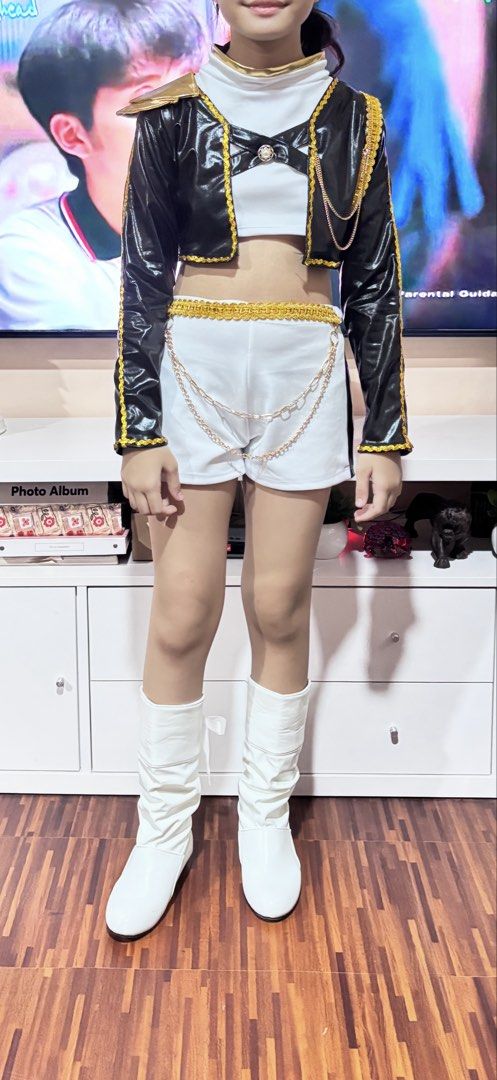 K-pop demon hunters costume (Category: Babies & Kids Fashion) located in Pasay City. Submitted by irenef0531 (Listing ID 1464697687, Image 1). Description: - Complete stage outfit in striking black, white, and gold - Includes cropped shiny jacket with gold trim and chains - Comes with a white mock neck crop top and matching shorts with a hanging chain belt - Includes white knee-high boots to complete the look - Ideal fit for kids and teens - for 