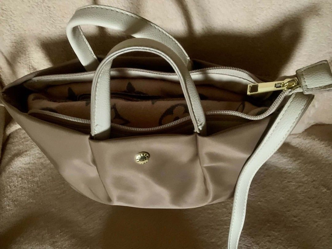 Legato Largo Bag (Category: Cross-body Bags) located in Dasmarinas. Submitted by pepperronnie (Listing ID 1464628803, Image 2). Description: This is a neutral beige multi-way tote & crossbody bag 🤎 ✨ Details: - Color: Warm taupe/beige body with cream/white handles & adjustable strap ​ - Material: Lightweight, smooth nylon + faux leather accents + gold snap button detail ​ - Versatile: Carry as a handbag/tote OR use the detachable strap for shoul