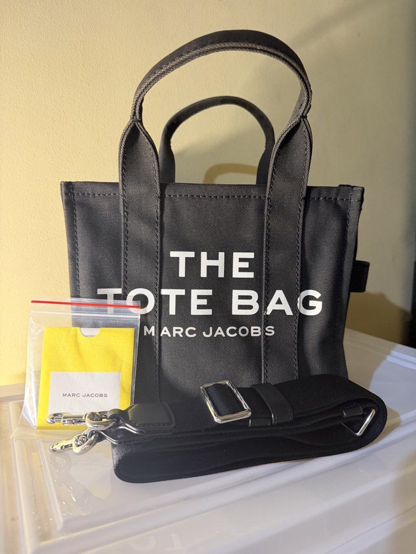 Marc Jacobs The Tote Bag Black Canvas Mini (Category: Tote Bags) located in Cebu City. Submitted by thelittlefindscbu (Listing ID 1464571543, Image 1). Description: • Brand: Marc Jacobs • Style: The Canvas Small Tote Bag • Color: Black • Size: Small • Material: Cotton canvas • With original adjustable/removable crossbody strap • Top handles + crossbody option • Zip-top closure • Classic white THE TOTE BAG / MARC JACOBS logo • Condition: Preloved 
