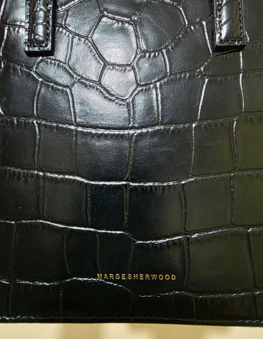 MARGE SHERWOOD Black Crocodile Mini Bag (Category: Purses & Pouches) located in Las Pinas. Submitted by andthelike (Listing ID 1464744244, Image 3). Description: - Brand: MARGE SHERWOOD - Material: Black crocodile embossed leather - Design: Structured square shape with flap closure and double top handles - Details: Gold-toned brand lettering on front - Style: Classic minimalist, highly versatile - Flaws: Minor scuff mark near one strap attachment