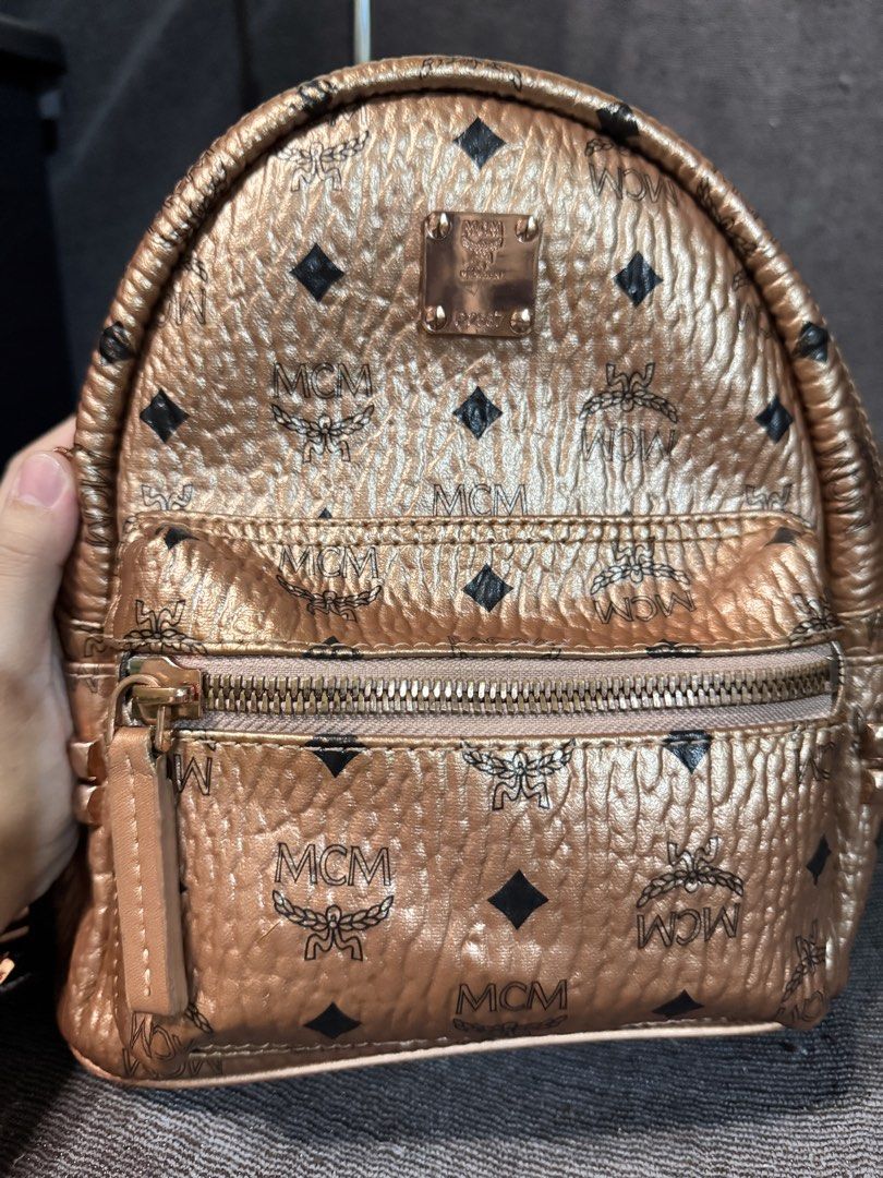 MCM Rose Gold Monogram Mini Backpack (Category: Luxury Bags & Wallets) located in Manila. Submitted by dearpinkcollections (Listing ID 1464676252, Image 2). Description: - MCM mini backpack in a chic rose gold metallic finish. - Features the signature all-over MCM monogram print. - Secure zip closure for the main compartment. - Convenient front zip pocket for essentials. - Adjustable shoulder straps for a comfortable fit. -slightly used.