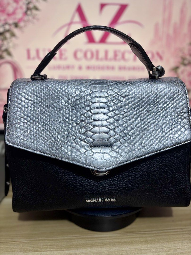 Michael Kors Black & Silver Textured Leather Handbag (Category: Luxury Bags & Wallets) located in Mandaluyong City. Submitted by annaziki2001 (Listing ID 1464573073, Image 2). Description: - Michael Kors black pebbled leather handbag - Silver textured flap with twist lock closure - Top handle and detachable shoulder strap included - Multiple interior compartments and zip pockets - Michael Kors logo detail on front and inside - Original strap is i