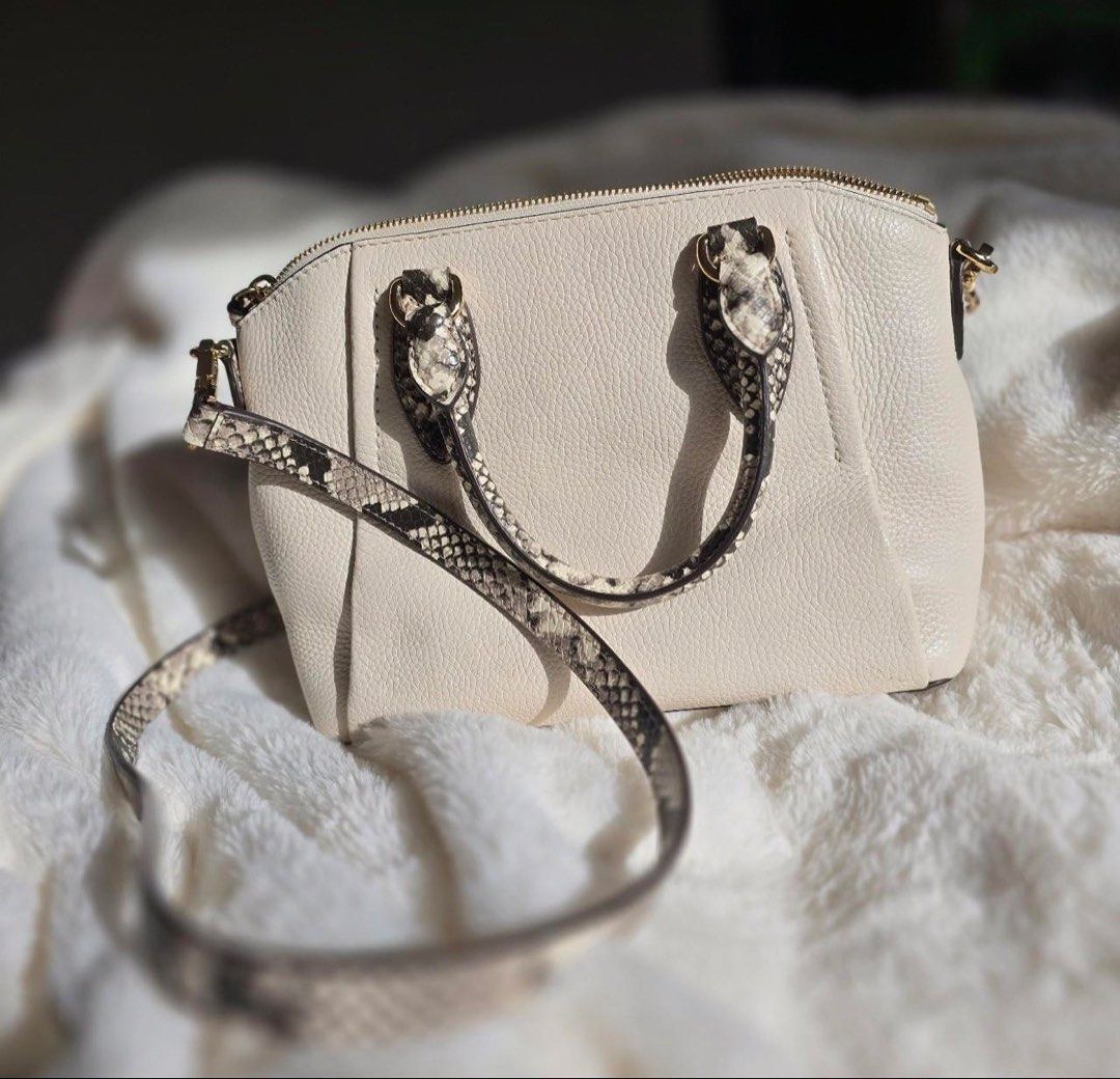 Michael Kors Cream Python Print Satchel Crossbody Bag (Category: Luxury Bags & Wallets) located in Manila. Submitted by kaia_studios (Listing ID 1464700991, Image 3). Description: Cream pebbled leather satchel with snakeskin-embossed handles and detachable crossbody strap. Gold-tone hardware and Michael Kors logo lettering on front. Zip top closure. Interior has custom fabric lining with multiple slip pockets and one zippered pocket with a leathe