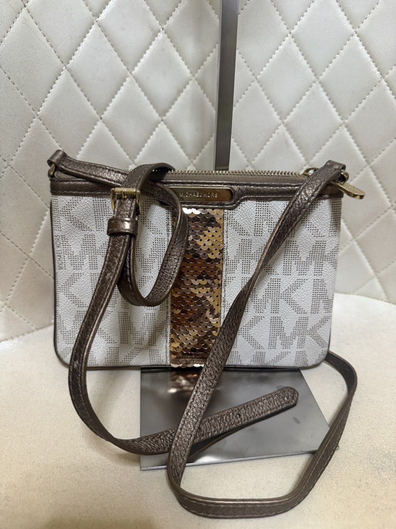 Michael Kors MK Logo Crossbody Bag with Sequins (Category: Cross-body Bags) located in Tarlac. Submitted by kayeshe (Listing ID 1464734564, Image 2). Description: - 100% Authentic - White and tan signature MK monogram print with bronze-gold sequin center stripe - Bronze metallic leather trim and adjustable strap - Secure top zip closure with gold-tone hardware - Interior features signature lining, slip pocket, and MK logo patch - Compact size, id