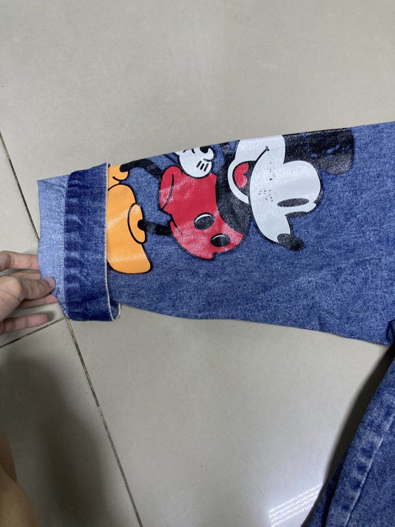 Mickey Mouse Denim Jacket (Category: Coats, Jackets and Outerwear) located in Bulacan. Submitted by fordypao (Listing ID 1464593197, Image 3). Description: - Classic blue denim jacket - Big Mickey Mouse graphic on the back - Mickey Mouse details on the sleeves - Button-up front closure - Functional front pockets - Ideal for Disney enthusiasts - Unique and eye-catching design.