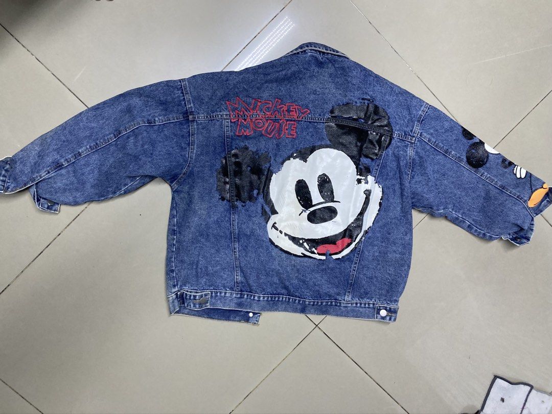 Mickey Mouse Denim Jacket (Category: Coats, Jackets and Outerwear) located in Bulacan. Submitted by fordypao (Listing ID 1464593197, Image 1). Description: - Classic blue denim jacket - Big Mickey Mouse graphic on the back - Mickey Mouse details on the sleeves - Button-up front closure - Functional front pockets - Ideal for Disney enthusiasts - Unique and eye-catching design.