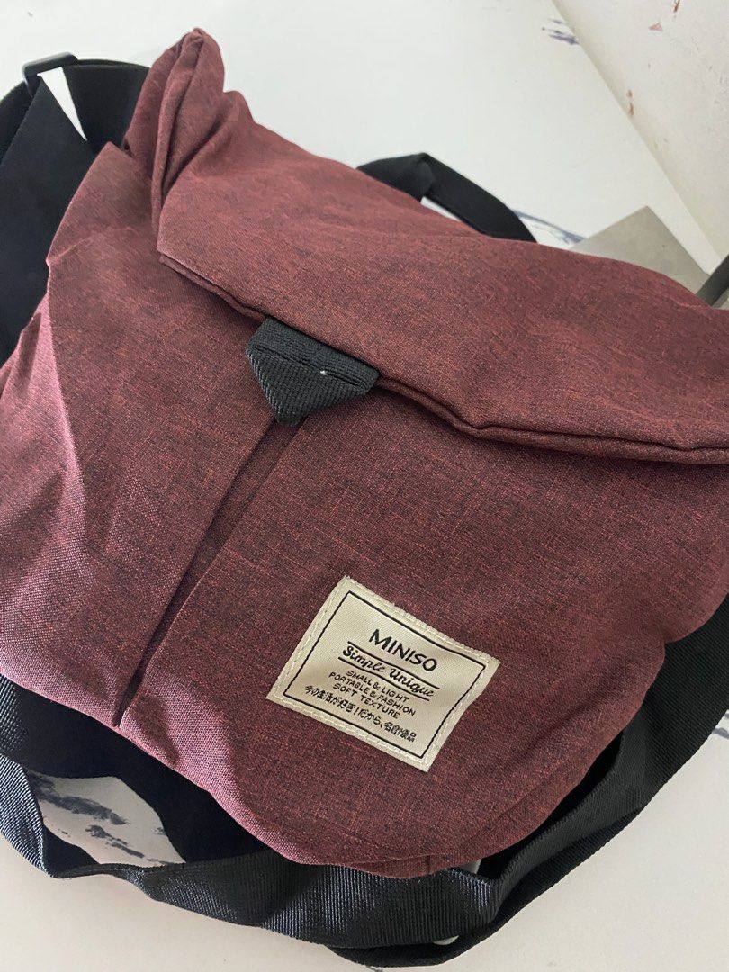MINISO Simple Unique Crossbody Bag Maroon (Category: Cross-body Bags) located in Manila. Submitted by onfleekapparelph (Listing ID 1464719368, Image 2). Description: - Brand: MINISO - Color: Maroon - Material: Soft texture, lightweight - Closure: Flap with secure strap - Strap: Adjustable black shoulder strap - Condition: Clean inside and out - Capacity: Roomy enough for daily essentials.