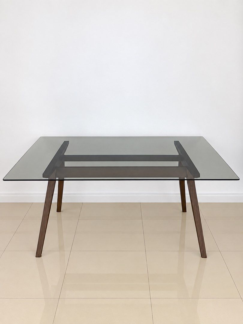 Modern Glass Top Dining Table with Wooden Frame (Category: Tables & Sets) located in San Juan City. Submitted by objectofmyaffection (Listing ID 1464719476, Image 1). Description: 67.25” length /29.5” height/35.5” width - Style: Modern minimalist rectangular dining table - Seating: Comfortably seats up to 6 people - Top: Sleek smoked glass surface - Base: Sturdy dark wood angled legs with a central wooden stretcher - Ideal For: Contemporary dinin