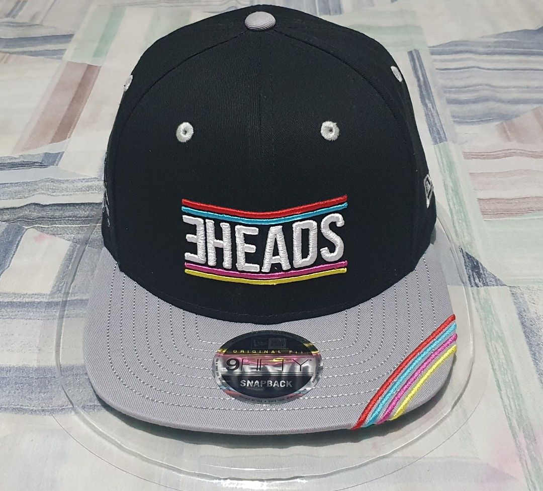New Era 9FIFTY Snapback Cap 3HEADS Collaboration (Category: Caps & Hats) located in Davao. Submitted by goldenphoenix_6cd296 (Listing ID 1464681706, Image 1). Description: - Brand: New Era - Style: 9FIFTY Snapback Cap - Front Logo: 3HEADS - Back Details: 'EST. 1989' and signature-like embroidery - Brim: Grey with colorful stripe detail - Sizing: One size fits most (adjustable snapback) - Condition: Brand new, still in original packaging.