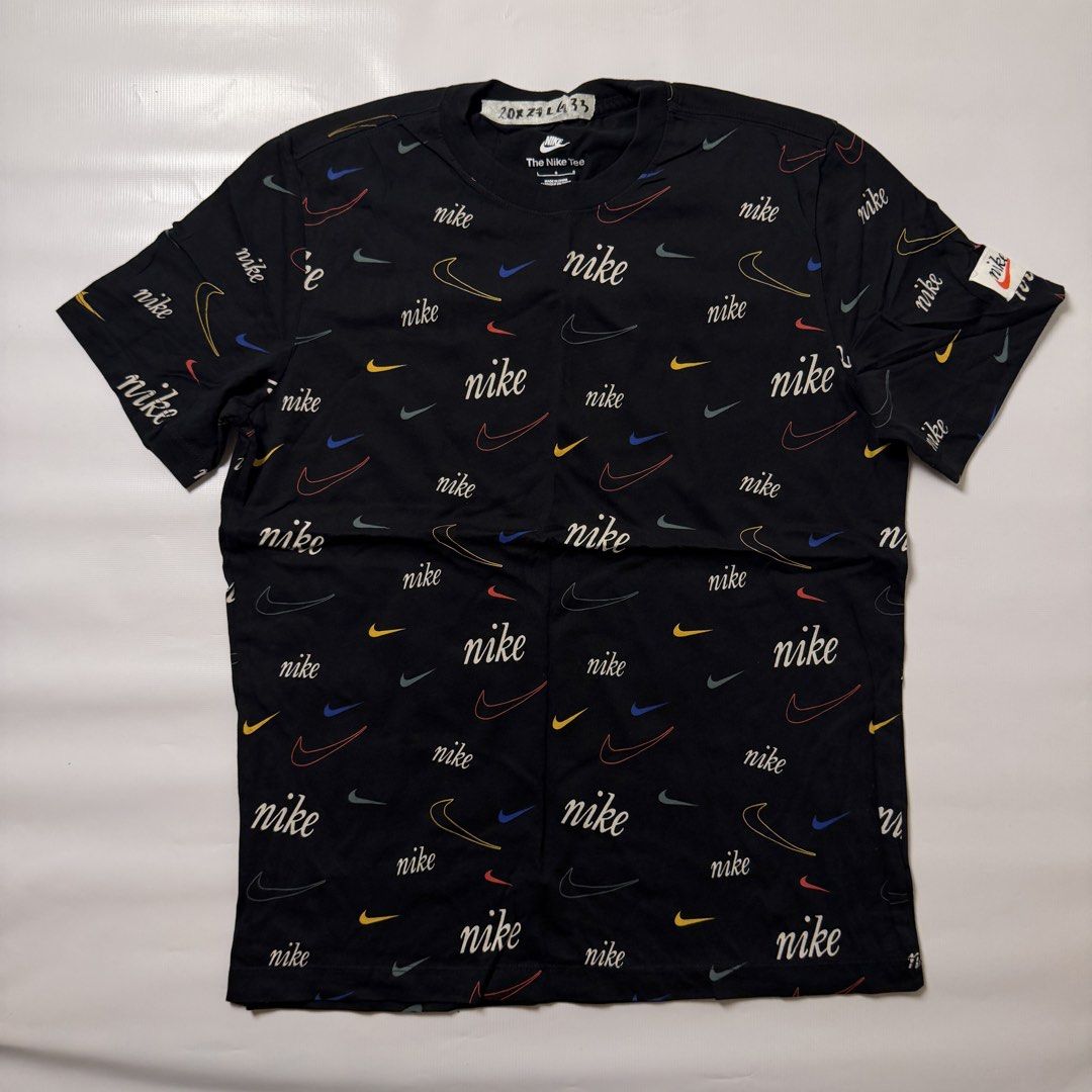 Nike All Over Print Multi Swoosh Tee Black (Category: Tshirts & Polo Shirts ) located in Manila. Submitted by johnedel_james (Listing ID 1464699234, Image 1). Description: - Brand: Nike - Condition: Brand new with interior tags intact - Size: Large (L) - Color: Black with multi-color all-over swoosh and script print - Material: 100% Cotton - Details: Short sleeves, crew neck, and vintage-style orange swoosh logo patch on the left sleeve - Origin: