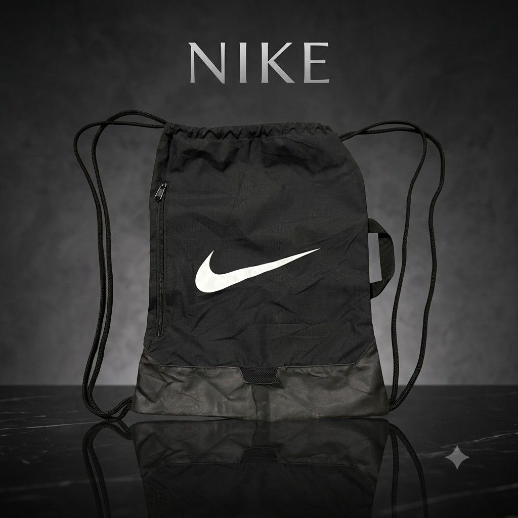 Nike Black Drawstring Gym Bag (Category: Backpacks) located in Carmen. Submitted by ar_thrift00 (Listing ID 1464715334, Image 1). Description: Black Nike drawstring backpack, 100% polyester body and lining. Large white swoosh on front. Vertical zip pocket on the side, plus a handy top grab handle. Drawstring cords work smoothly. Clean inside tag showing material breakdown. Great daily gym or school sack..