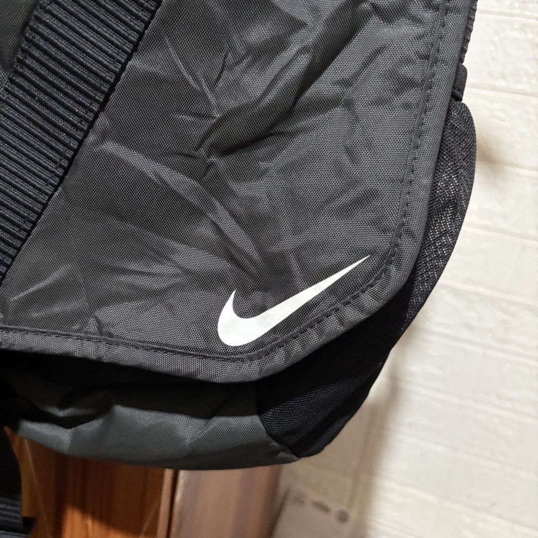 Nike Black Messenger Bag with Adjustable Strap and Buckle (Category: Sling Bags) located in Carmen. Submitted by rr_thrifts (Listing ID 1464722165, Image 2). Description: - Brand/Item: Black Nike Messenger Bag - Material: Durable nylon that holds its shape well - Design: Front flap with white Nike swoosh, secure buckle closure, and strap with repeated Nike lettering - Storage: Interior zippered pockets and organizational compartments - Versatilit