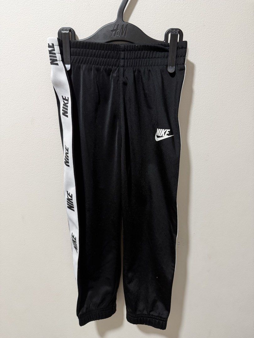 Nike Black White Tape Tracksuit Set (Category: Babies & Kids Fashion) located in Manila. Submitted by dejavogue.ph (Listing ID 1464644545, Image 3). Description: - Authentic Nike tracksuit set - Classic black with white Nike tape detail on sleeves and legs - Full zip jacket with convenient pockets - Comfortable pants with elastic waistband - Versatile for everyday wear or athletic activities.