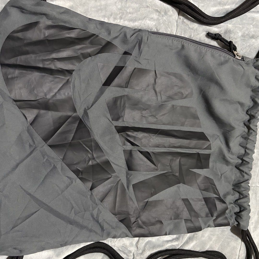 Nike Grey Drawstring Gym Bag with Zipper Pocket (Category: Backpacks) located in Carmen. Submitted by rr_thrifts (Listing ID 1464722963, Image 2). Description: - Brand: Nike - Color: Grey with large geometric graphic print - Material: 100% polyester (verified by inside tag) - Storage: Spacious main compartment with drawcord closure plus a secure side zipper pocket - Design: Lightweight, packable, and easy to carry - Condition: Excellent / Ready t
