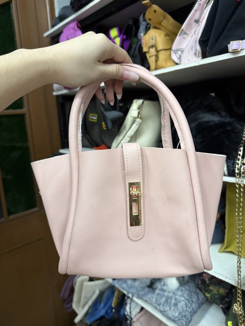 Pink handbag with gold clasp (Category: Luxury Bags & Wallets) located in Manila. Submitted by fastlion.584bdf (Listing ID 1464739047, Image 1). Description: - Color: Pink - Material: Soft structured fabric - Closure: Gold-tone metal clasp on front strap - Interior: Clean, unlined white fabric - Features: Dual top handles, compact size ideal for everyday use - Condition: Minor signs of wear on the exterior surface.