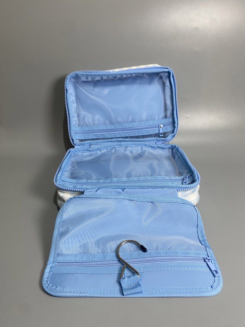 Popique Blue Gingham Hanging Toiletry Bag (Category: Purses & Pouches) located in Davao. Submitted by brandedthrift.134 (Listing ID 1464735711, Image 2). Description: - Brand: Popique - Condition: Brand new with tags in original plastic zip bag - Design: Blue and white gingham pattern with pink branding logo and bright yellow top handle - Features: Built-in hanging hook and multiple zippered compartments with clear plastic lining.