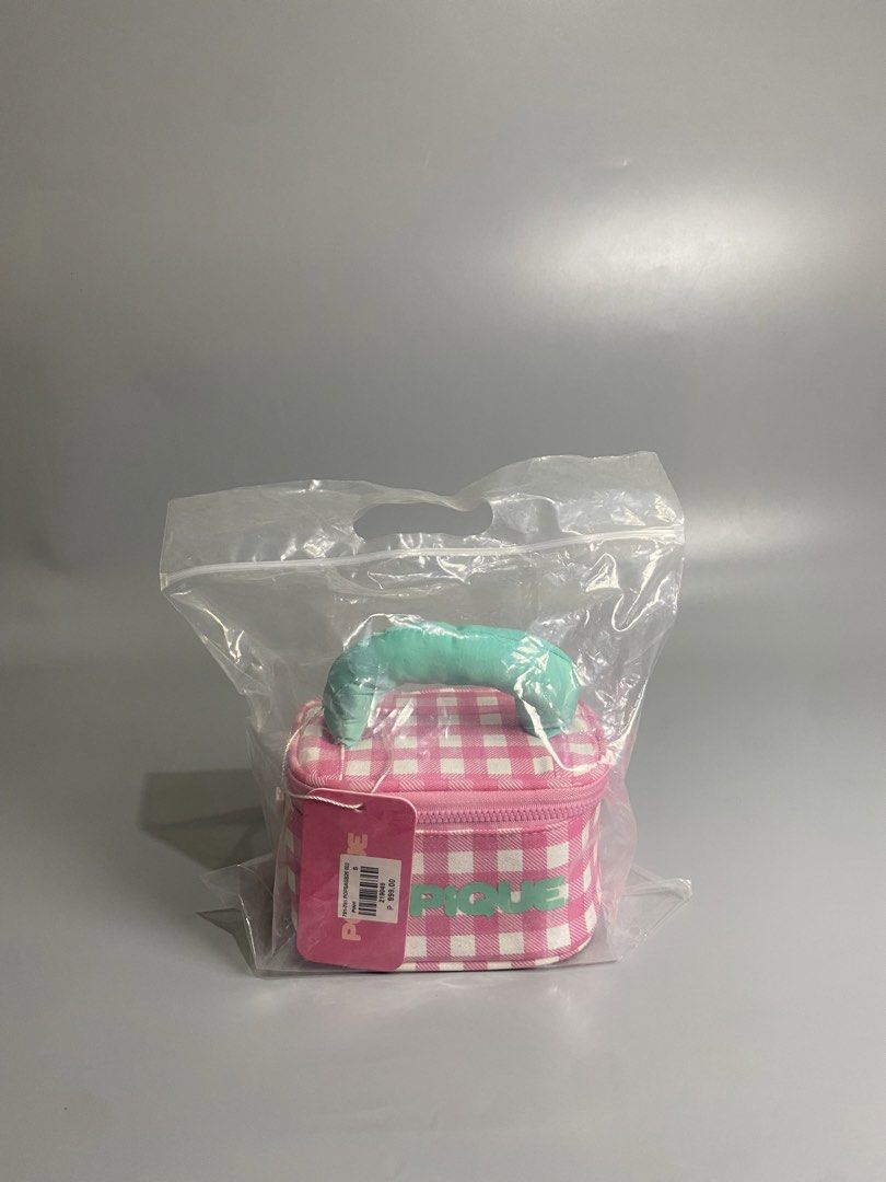 POPIQUE Pink Gingham Makeup Vanity Bag with Mirror (Category: Purses & Pouches) located in Davao. Submitted by brandedthrift.134 (Listing ID 1464736491, Image 3). Description: - Brand: POPIQUE (Brand New with Tags) - Design: Pink & white gingham pattern with teal puffy handle and matching front text - Interior: Pink lining with built-in mirror inside the lid - Closure: Zip-around closure - Packaging: Packed in a clear plastic storage bag.