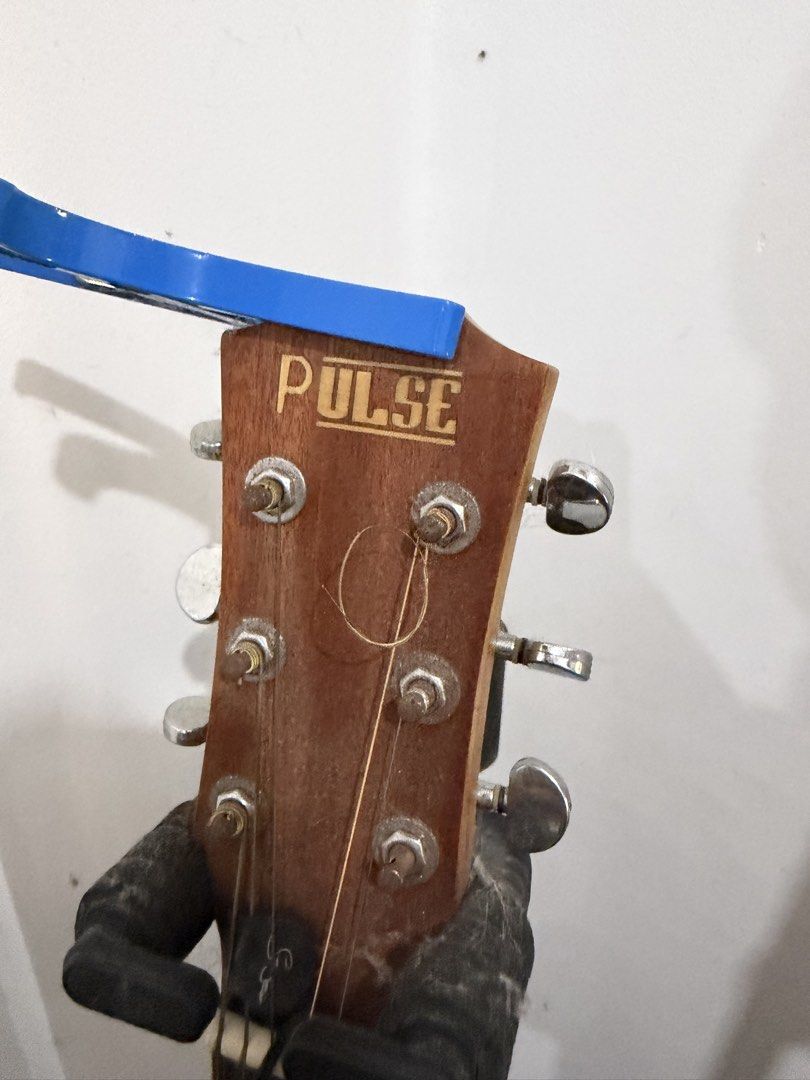 Pulse Acoustic Guitar (Category: Musical Instruments) located in Manila. Submitted by ramonrueda37147 (Listing ID 1464594387, Image 3). Description: - Acoustic guitar with "PULSE" headstock. - Six tuning pegs and strings. - Includes a blue capo. - Fretboard visible. -Free guitar stand -missing #1 - Free Guitar Stand .