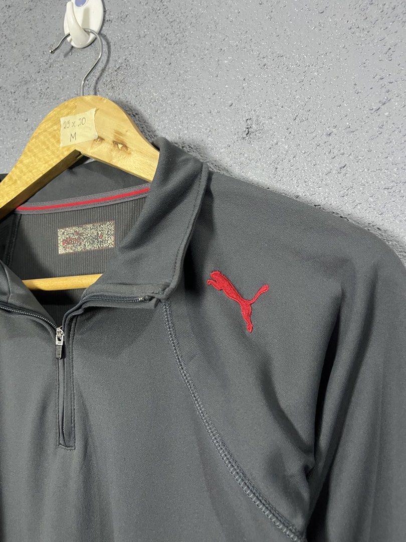 Puma Dark Grey Half Zip Pullover Size M (Category: Coats, Jackets and Outerwear) located in Famy. Submitted by basicthrifted (Listing ID 1464704106, Image 3). Description: - Brand: Puma - Style: Half-zip pullover with long sleeves - Color: Dark grey with red accents - Logo: Red embroidered Puma logo on left chest - Details: Ribbed collar with thin red accent line, Made in Japan inner tag - Size: M (approx. 25" length by 20" width) - Condition/Use