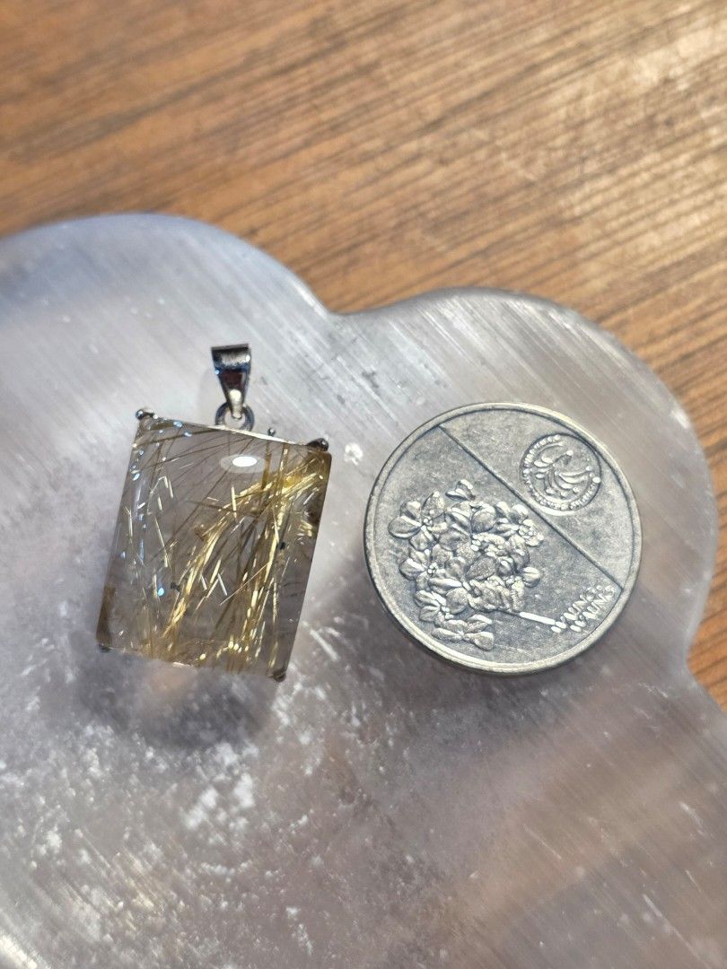 Rectangle Rutilated Quartz Pendant with Gold Needles (Category: Charms) located in Manila. Submitted by alyayeah (Listing ID 1464612806, Image 2). Description: - Rectangular clear quartz pendant - Features visible gold-colored needles inside - Set in s925 silver - Includes a bail for easy necklace attachment - Piso coin for size reference but serious buyers can ask for measurements.