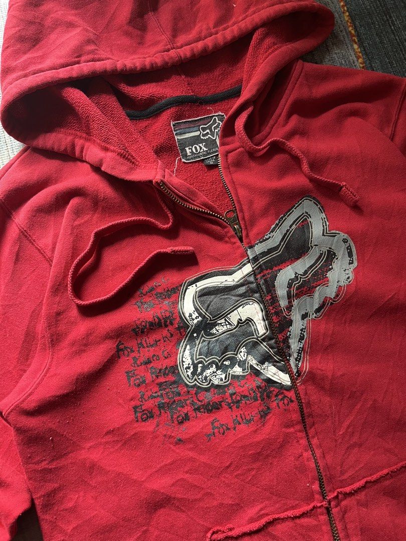 Red Fox Racing Zip-Up Hoodie (Category: Coats, Jackets and Outerwear) located in Puerto Princesa. Submitted by dijaydj28 (Listing ID 1464588638, Image 3). Description: - Classic red Fox Racing zip-up hoodie - Features iconic Fox head logo and graphic text on front - Full zip closure - Front pockets - Hood drawstrings intact - Minor signs of wear (small snag near shoulder) - Perfect for casual wear.