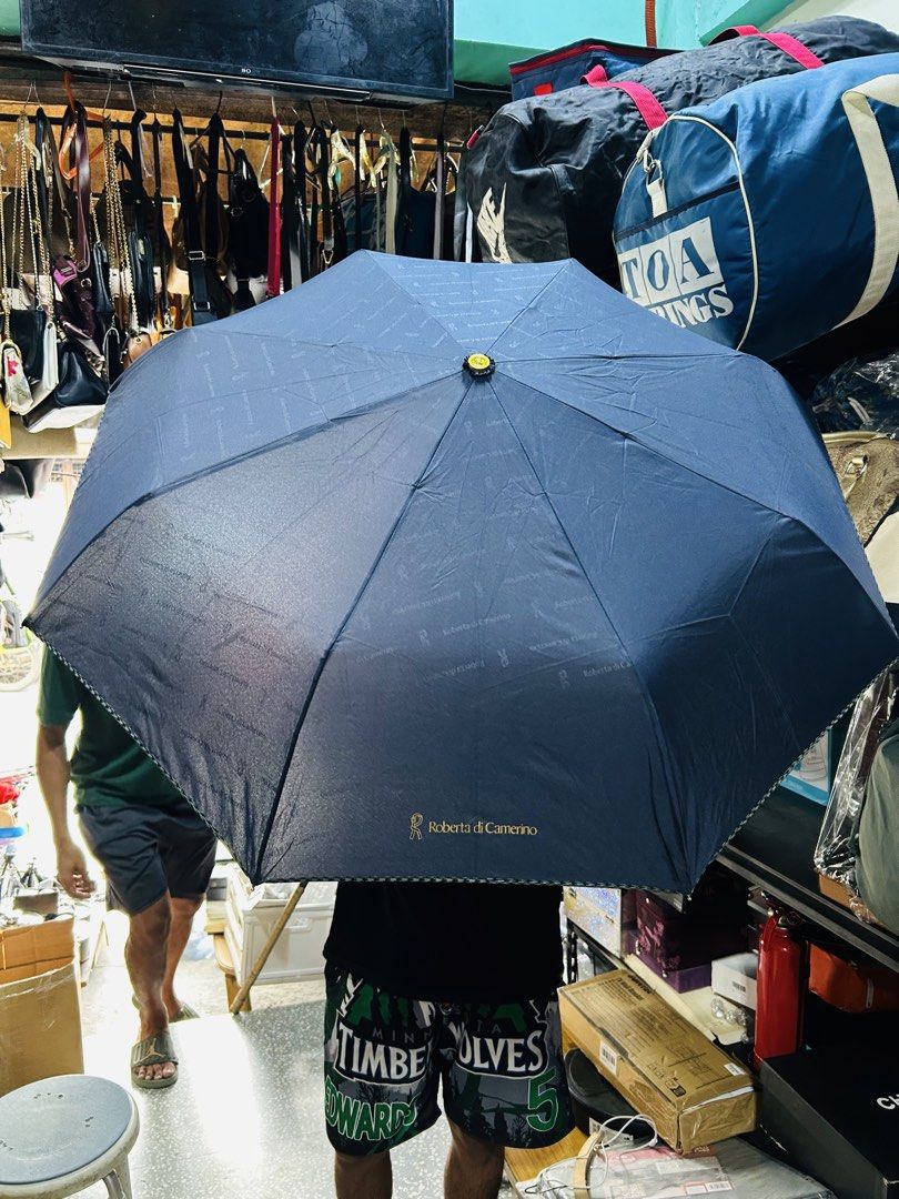 Roberta di Camerino Navy Blue Umbrella (Category: Umbrellas) located in Manila. Submitted by starbalesukandjapansurplus (Listing ID 1464585273, Image 3). Description: - Authentic Roberta di Camerino navy blue umbrella - Features the iconic signature logo pattern all over the canopy - Compact and foldable design for convenient storage - Elegant gold accent on the handle - Essential accessory for rainy weather.