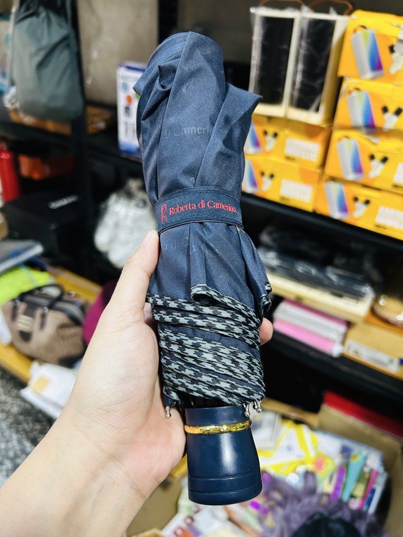 Roberta di Camerino Navy Blue Umbrella (Category: Umbrellas) located in Manila. Submitted by starbalesukandjapansurplus (Listing ID 1464585273, Image 2). Description: - Authentic Roberta di Camerino navy blue umbrella - Features the iconic signature logo pattern all over the canopy - Compact and foldable design for convenient storage - Elegant gold accent on the handle - Essential accessory for rainy weather.