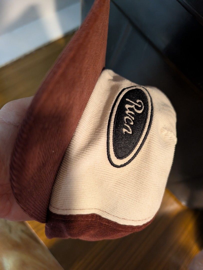RVCA Badge Snapback (Good as new) (Category: Caps & Hats) located in Naga. Submitted by kenshin78 (Listing ID 1464729776, Image 2). Description: - Brand: RVCA - Material: Brown and white corduroy fabric - Design: Structured crown, flat brim, and oval embroidered logo patch on the front - Closure: Adjustable plastic snapback with a small logo tab - Condition: good as new / Excellent quality - Perfect for daily streetwear and casual outfits.