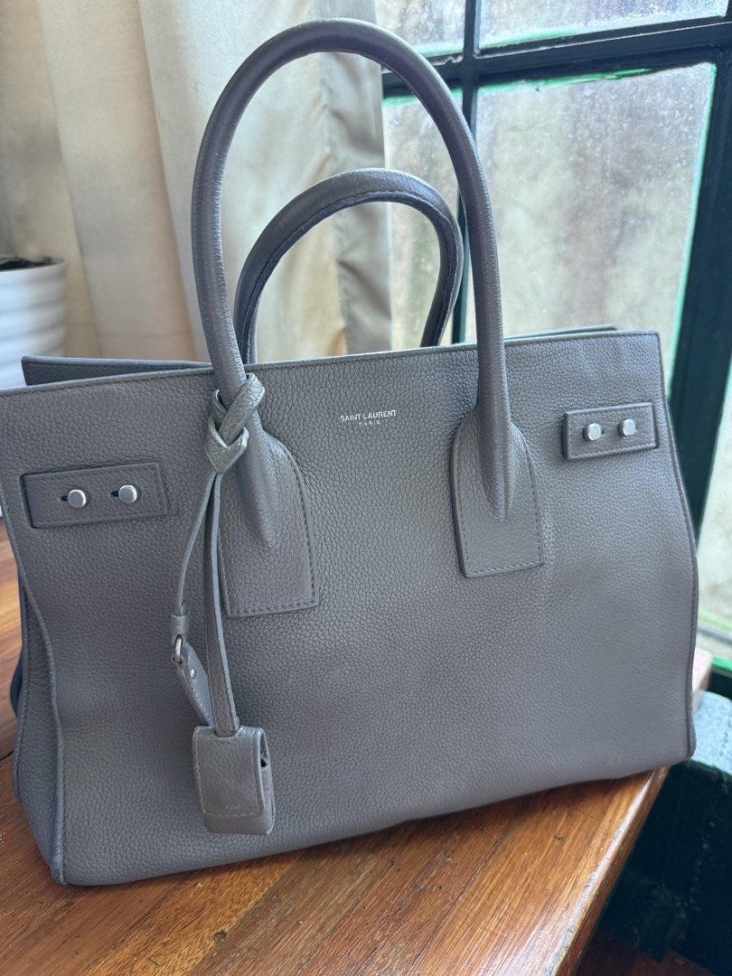 Saint Laurent Sac De Jour Bag Grey (Category: Luxury Bags & Wallets) located in Baguio. Submitted by reimaginedbags (Listing ID 1464716886, Image 1). Description: - Brand: Saint Laurent (YSL) - Model: Sac De Jour - Material: Premium textured grey leather - Hardware: Silver-tone with front logo stamp - Handles: Double top handles - Includes: Matching padlock and keys in a leather clochette - Interior: Fabric lining with a convenient zipped pouch -