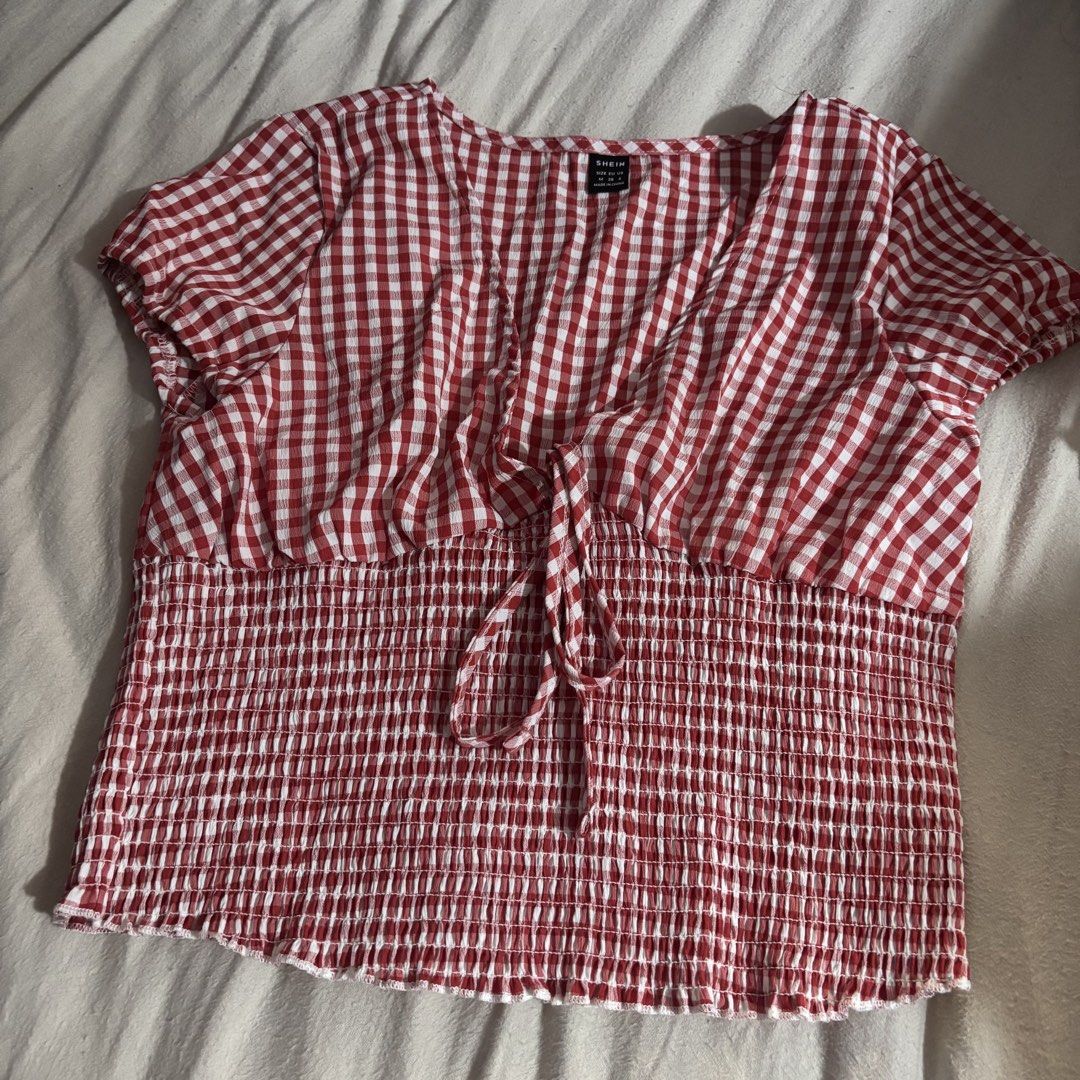 SHEIN Red Gingham Smocked Tie Front Top Size M (Category: Blouses) located in Cainta. Submitted by kairus.luckyfind (Listing ID 1464643997, Image 1). Description: NEVER USED - Cute red and white gingham top - Brand: SHEIN - Features: Tie front detail, smocked waist, short sleeves - Style: Casual, easy to wear - Pairs well with: Jeans or shorts.