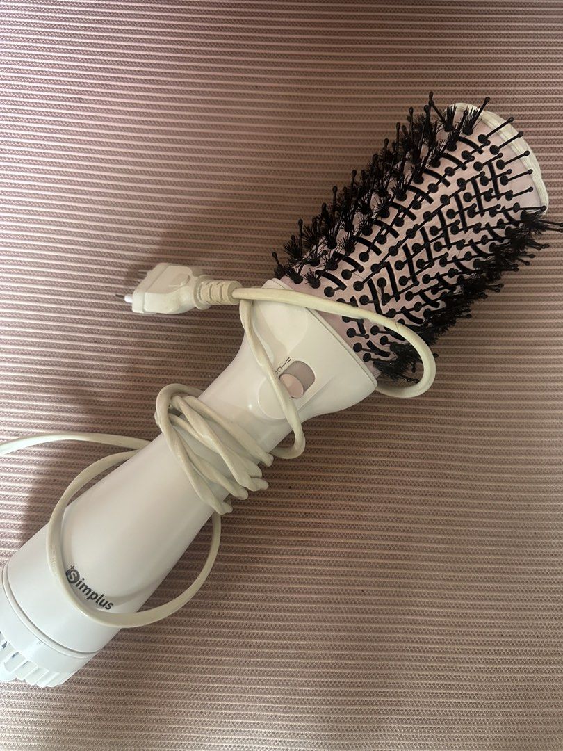 Simplus Hair Dryer Brush (Category: Hair) located in Dasmarinas. Submitted by maecybee (Listing ID 1464604094, Image 1). Description: - White hair dryer brush with a vibrant pink barrel - Features a tangle-free swivel cord for effortless maneuverability - Multiple heat settings to suit your hair type and styling needs - Combines drying and styling in one easy step - Designed for user-friendly operation.