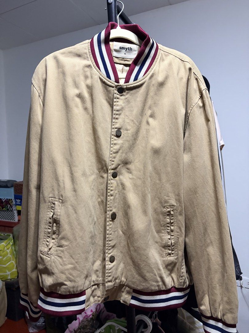Smyth Varsity Bomber Jacket Tan Khaki Size XL (Category: Coats, Jackets and Outerwear) located in Manila. Submitted by finderskeepersmnl_092026 (Listing ID 1464744169, Image 1). Description: - Brand/Style: Smyth tan khaki varsity jacket with a classic collegiate aesthetic - Size: XL - Details: Maroon, white, and blue striped ribbing on the collar, cuffs, and hem - Closure: Snap button front - Pockets: Two vertical front pockets - Material: Sturdy