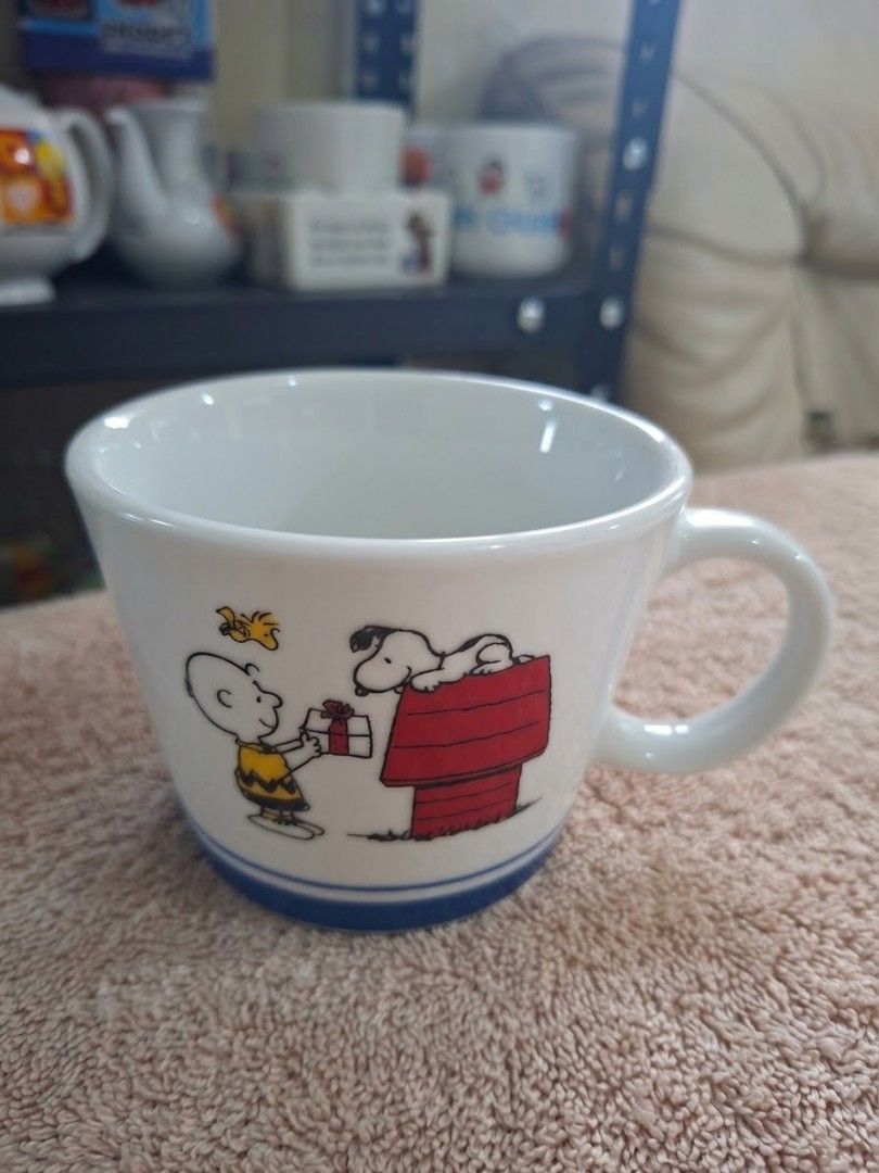 Snoopy Mug (Category: Coffee & Tea Tableware) located in Consolacion. Submitted by luxekerei (Listing ID 1464769102, Image 2). Description: - to be a 2016 Snoopy Christmas mug released as a promotional item by Mister Donut in Japan, featuring an illustration of Charlie Brown handing a gift to Snoopy on his red doghouse with Woodstock overhead, accented by a blue stripe along the base..
