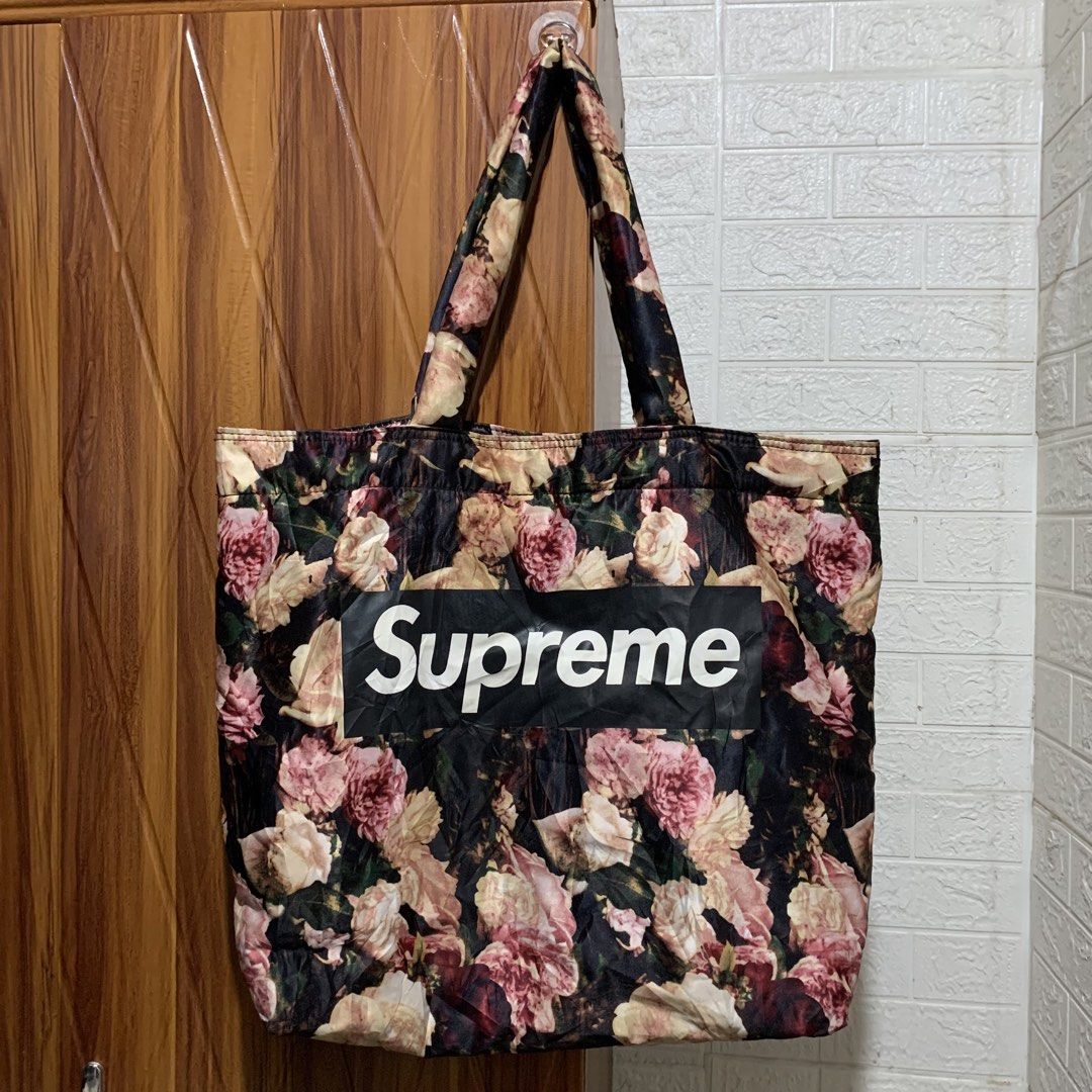 Supreme Floral Tote Bag (Category: Tote Bags) located in Carmen. Submitted by rr_thrifts (Listing ID 1464730065, Image 1). Description: - Supreme floral print tote bag (black, pink, and cream tones) - Features iconic black box logo with white Supreme branding on the front - Roomy everyday carryall with double shoulder straps - Black fabric interior lining with convenient internal pocket - Secure magnetic snap closure - Condition: Excellent - PM f