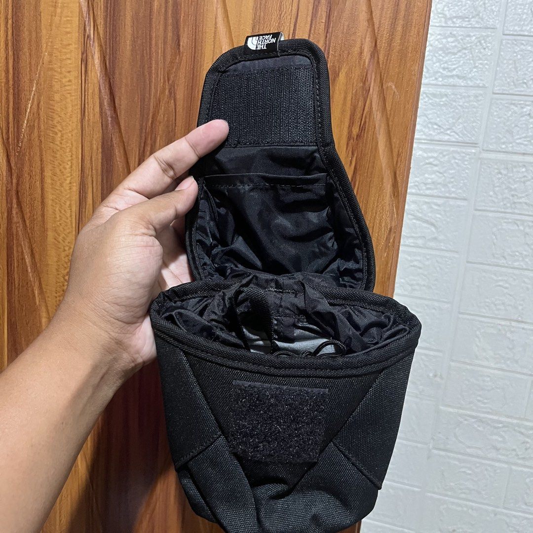 The North Face Black Utility Pouch (Category: Belt bags, Clutches and Pouches) located in Carmen. Submitted by rr_thrifts (Listing ID 1464728438, Image 3). Description: - Brand: The North Face - Color: Black - Condition: Brand new with red tag attached - Material: Durable canvas fabric with branded front tag - Features: MOLLE webbing straps and snap buttons on the back - Closure: Drawstring main closure under the flap - Interior: Includes a small