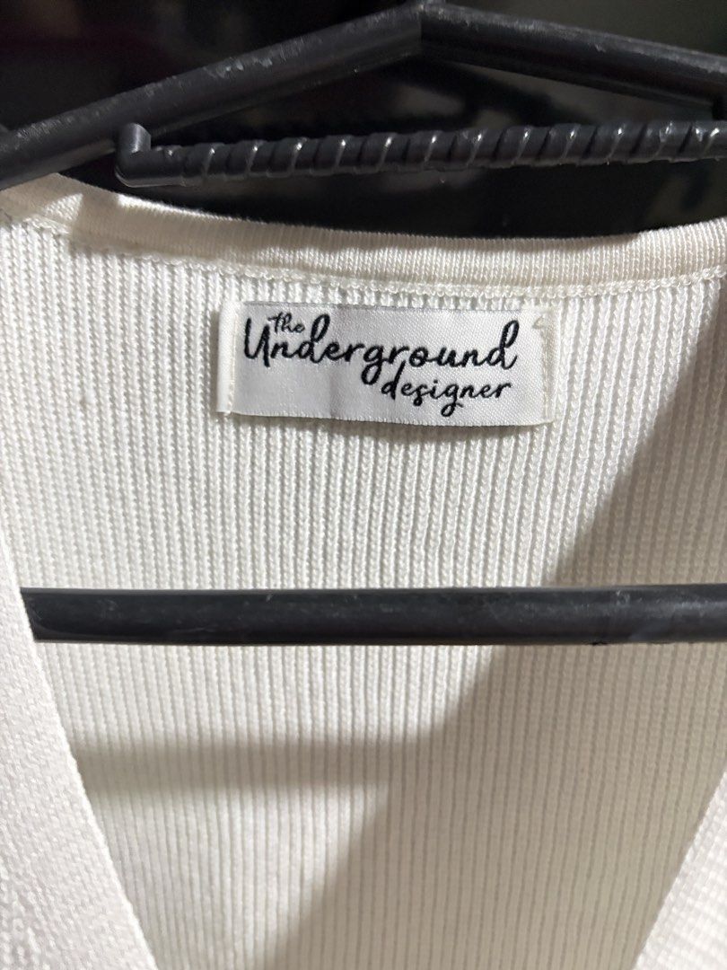 The Underground Designer White Knit Button-Up Vest (Category: Sleeveless) located in Valenzuela. Submitted by celineyap04 (Listing ID 1464623597, Image 2). Description: - Brand: The Underground Designer - Color: White - Style: Knit Vest - Neckline: V-neck - Closure: Button-up front - Sleeves: Sleeveless - Texture: Ribbed throughout - Estimated Size: Small (based on tag) - Features: Great layering piece, simple and classic style.
