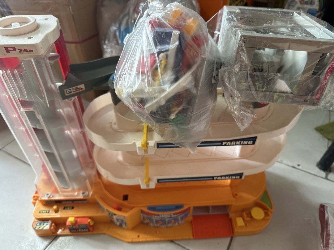 Tomica Parking Garage Playset with Accessories (Category: Vehicle & Diecast Models) located in Cainta. Submitted by shopbyyna (Listing ID 1464622492, Image 1). Description: - Tomica parking garage playset - Main garage: orange and white with ramps and elevator - Includes separate grey 'Auto Lift Parking' unit - Various accessories and parts included - Some parts labeled 'Tomica Parts 200 (As is)' - Perfect for car toy enthusiasts and collectors.