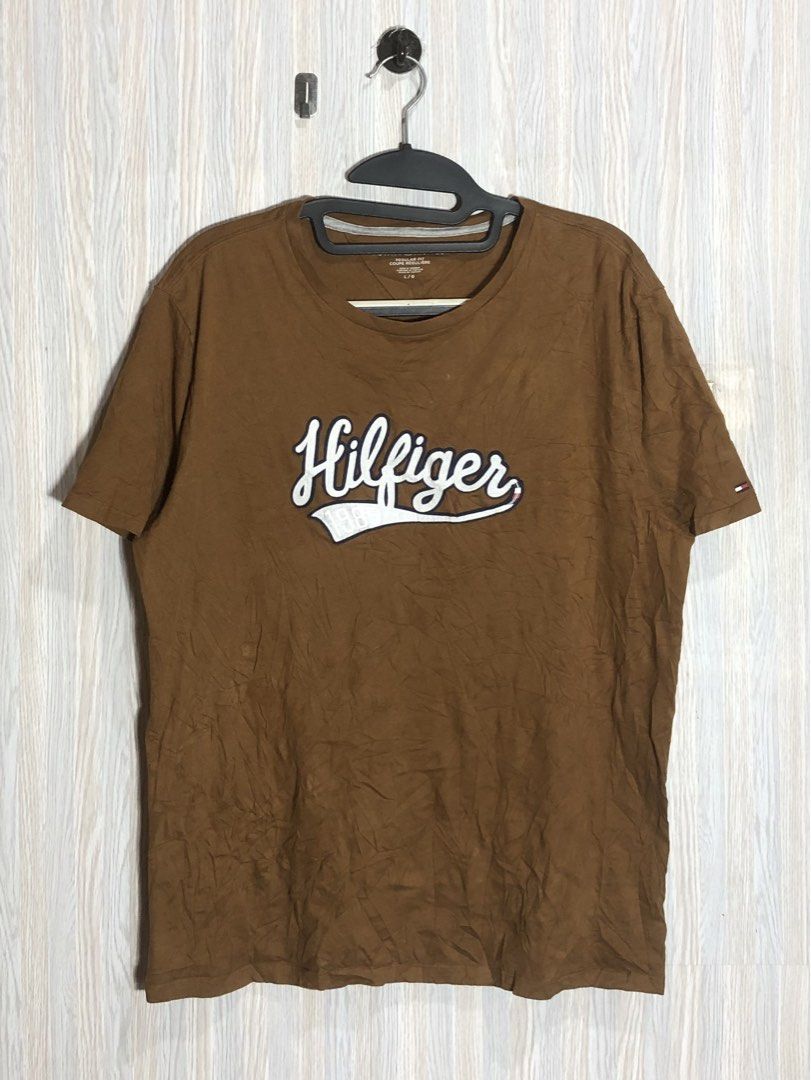 Tommy Hilfiger Brown Script Logo T-Shirt Size L (Category: Tshirts & Polo Shirts ) located in Montevista. Submitted by rdthriftshub (Listing ID 1464756008, Image 1). Description: - Brand: Tommy Hilfiger - Style: Regular fit crew neck t-shirt - Color: Brown - Size: L/G - Material: 100% cotton (Made in Vietnam) - Design: Large embroidered white script logo with '1985' on the chest - Details: Contrast inner neck taping and inner side wash tag - Cond