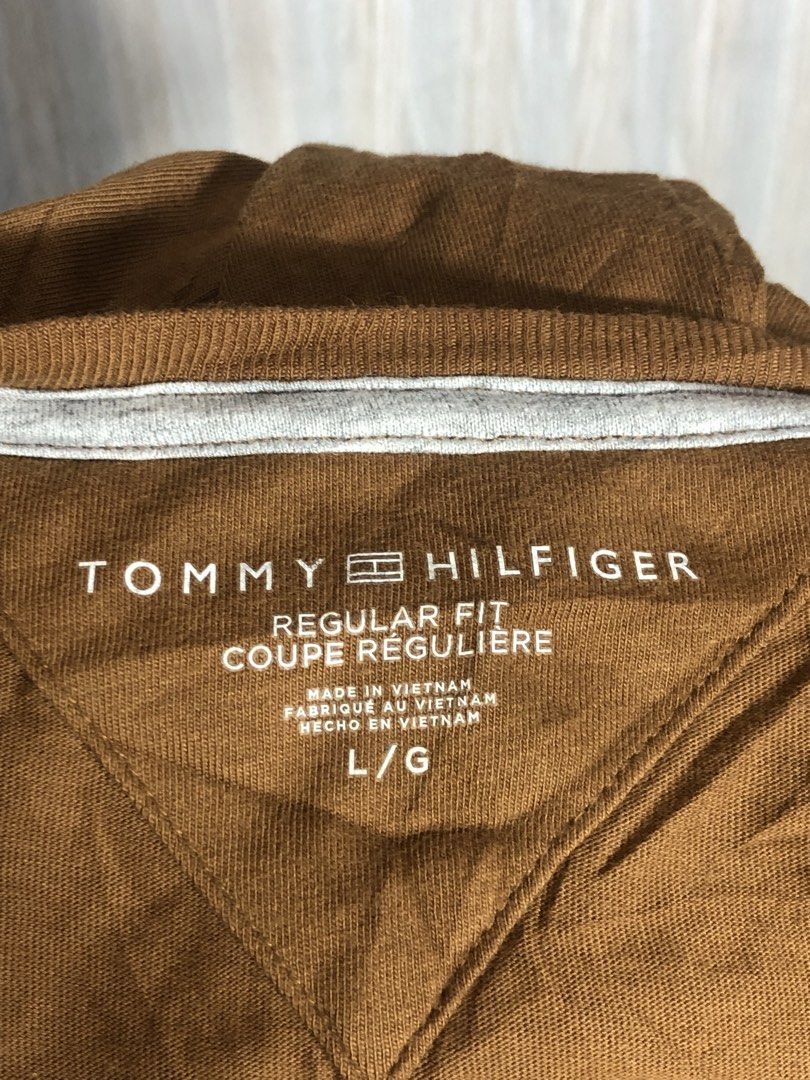 Tommy Hilfiger Brown Script Logo T-Shirt Size L (Category: Tshirts & Polo Shirts ) located in Montevista. Submitted by rdthriftshub (Listing ID 1464756008, Image 3). Description: - Brand: Tommy Hilfiger - Style: Regular fit crew neck t-shirt - Color: Brown - Size: L/G - Material: 100% cotton (Made in Vietnam) - Design: Large embroidered white script logo with '1985' on the chest - Details: Contrast inner neck taping and inner side wash tag - Cond